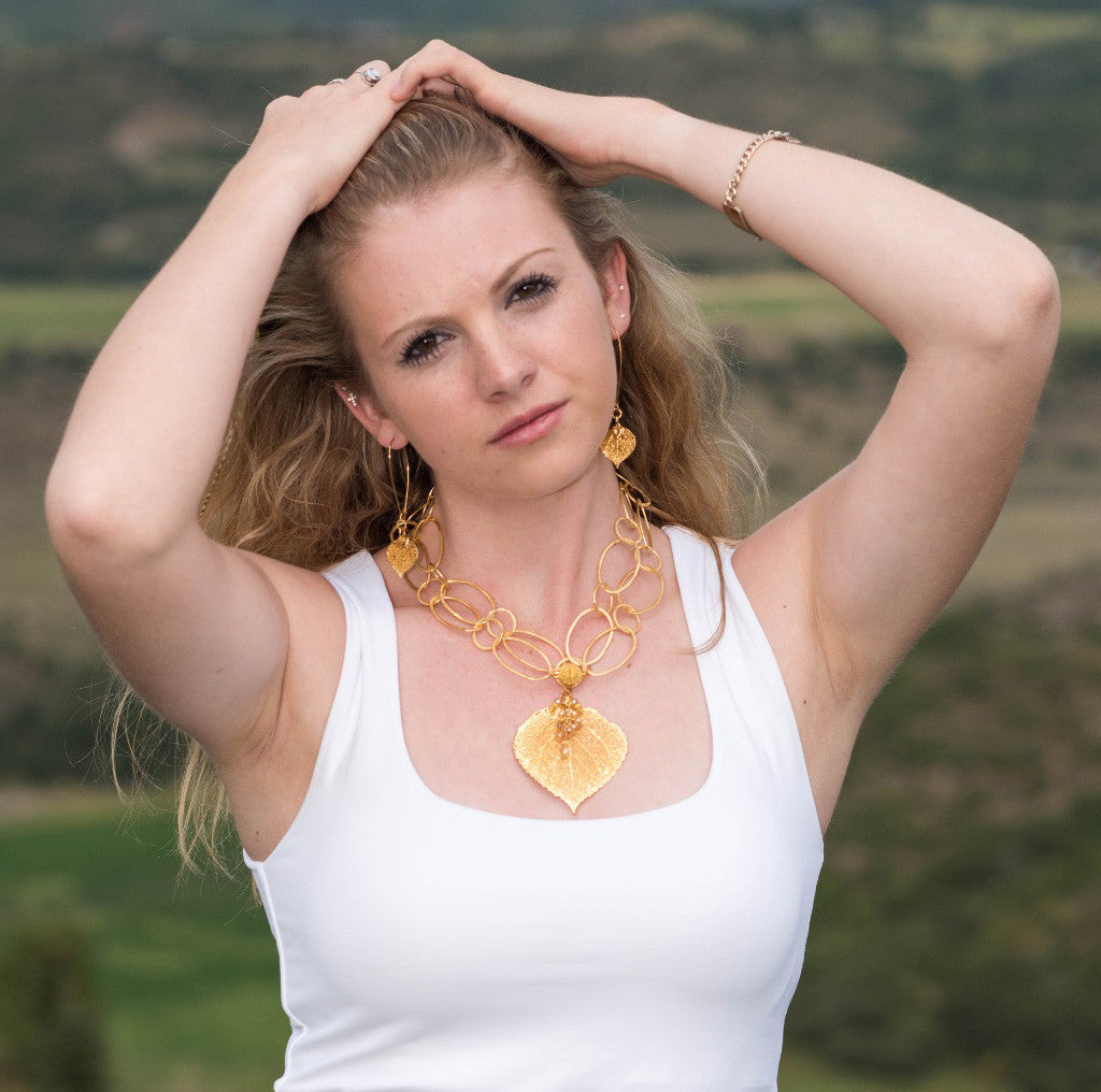 Signature gold chain combined with a large gold leaf and crystal dangles creates this striking necklace