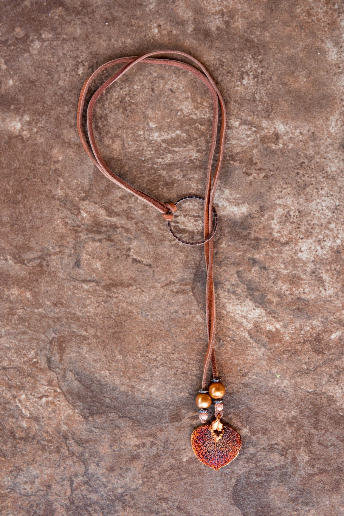Two bronze pearls, copper leaf, brown leather and pounded copper ring